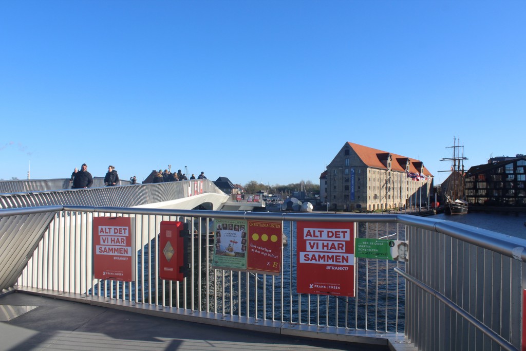 Kommunalvalgplaker på gelænder af "Inderhavnsbroen". udsigt mod Nordatlantentens Brygge med pakhus opfæørt 1766-67 på Christianhavn. Foto i retning syd den 30. oktober 2017 af Erik K ASbrahamsen.